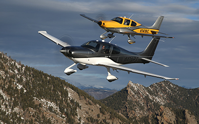 Two cirrus aircrafts flying over mountains